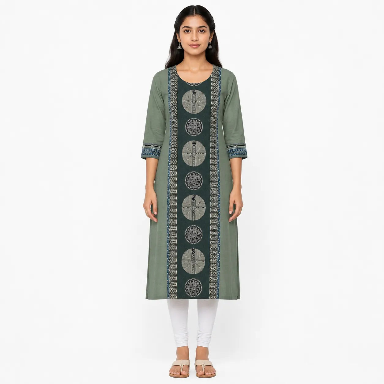 A woman modeling a sage green kurta with a vertical black panel featuring circular geometric patterns and blue patterned trim on the sleeves and neckline, paired with white leggings and beige sandals against a plain white background.