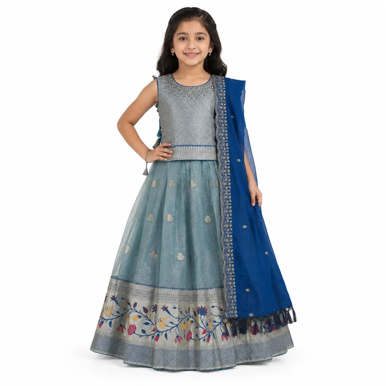 A young girl modeling a traditional Indian outfit consisting of a light blue flared skirt with floral embroidery, a silver-beaded sleeveless top, and a royal blue dupatta with gold borders, set against a plain white background.