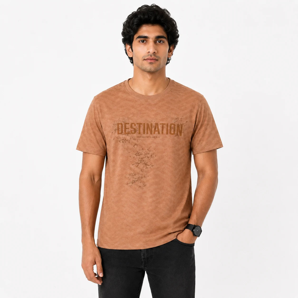 A man wearing a brown acid-wash graphic t-shirt with 'DESTINATION' printed across the chest, paired with black jeans, against a plain white background.