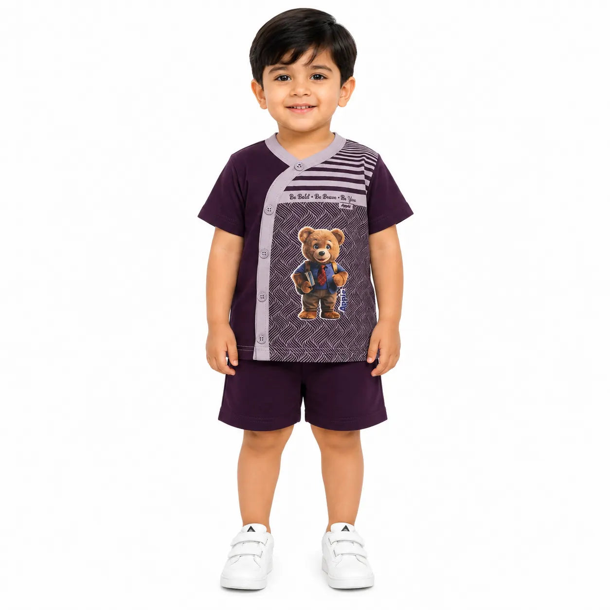 A young boy modeling a two-piece pajama set consisting of a short-sleeve top and shorts in deep purple. The top features a central graphic of a teddy bear wearing a suit on a patterned background, with striped details on the sleeves.