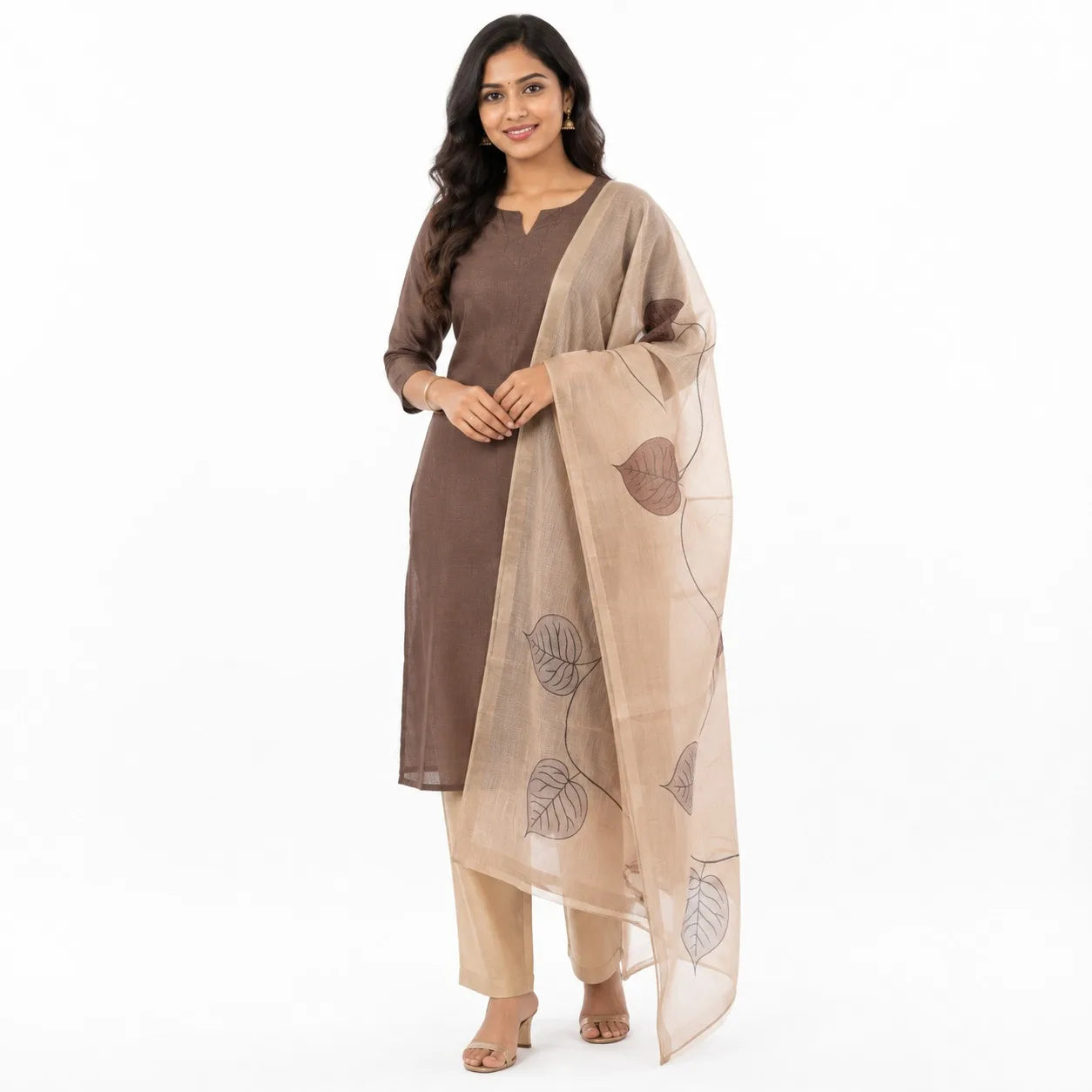 A woman modeling a traditional Indian outfit consisting of a brown kurta, beige trousers, and a beige dupatta with brown leaf prints, set against a plain white background.