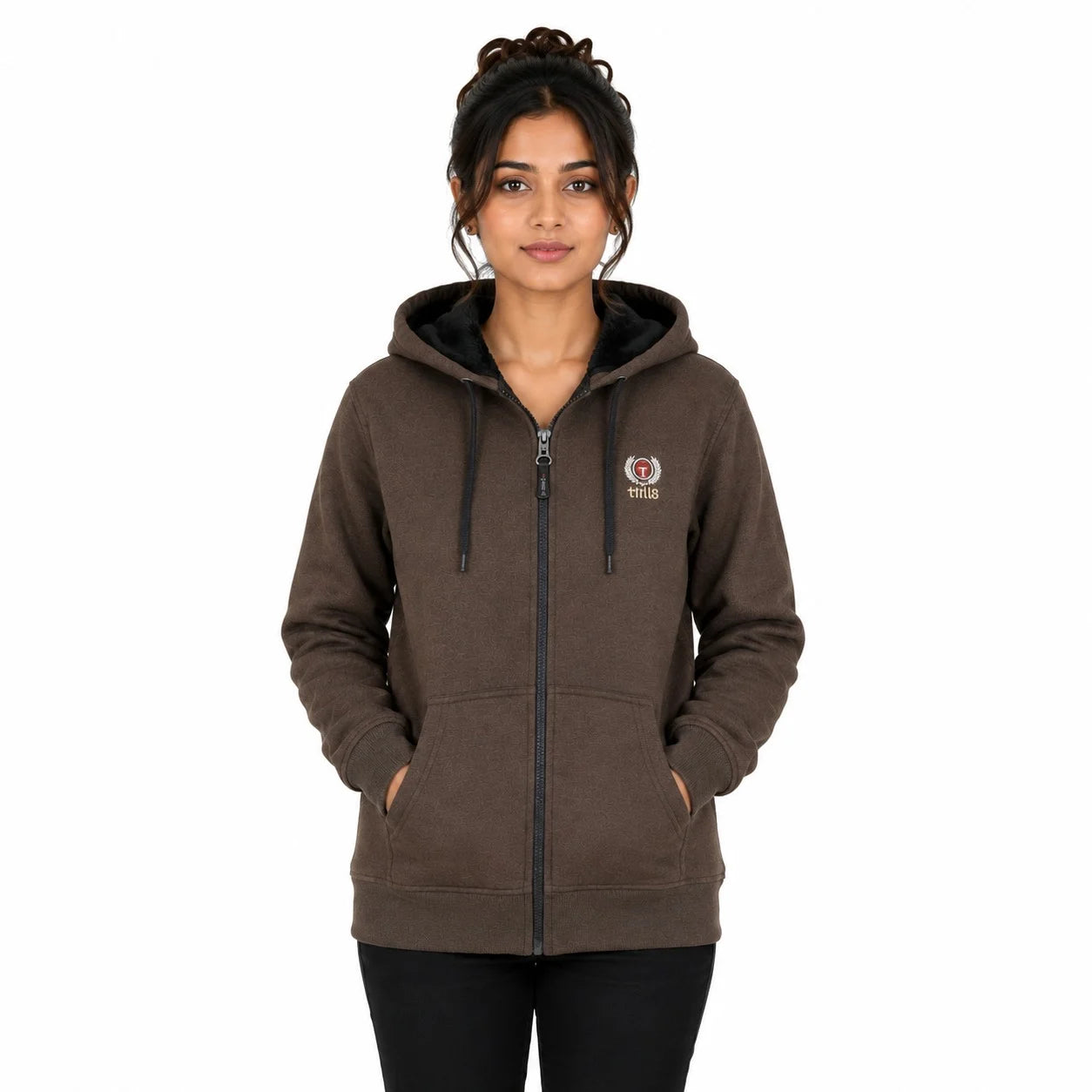 A woman wearing a dark brown zip-up hoodie with a black drawstring hood and a small circular logo on the left chest, paired with black pants, against a plain white background.