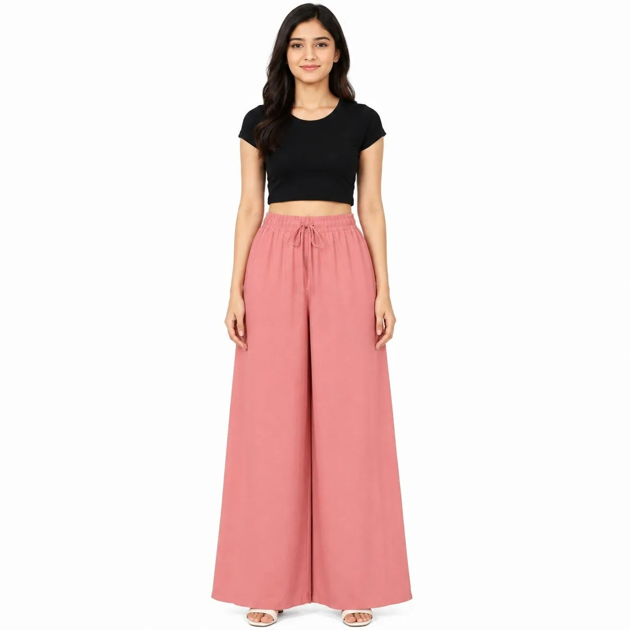 A woman modeling a two-piece outfit consisting of a black short-sleeve crop top and dusty pink wide-leg drawstring pants, set against a plain white background.