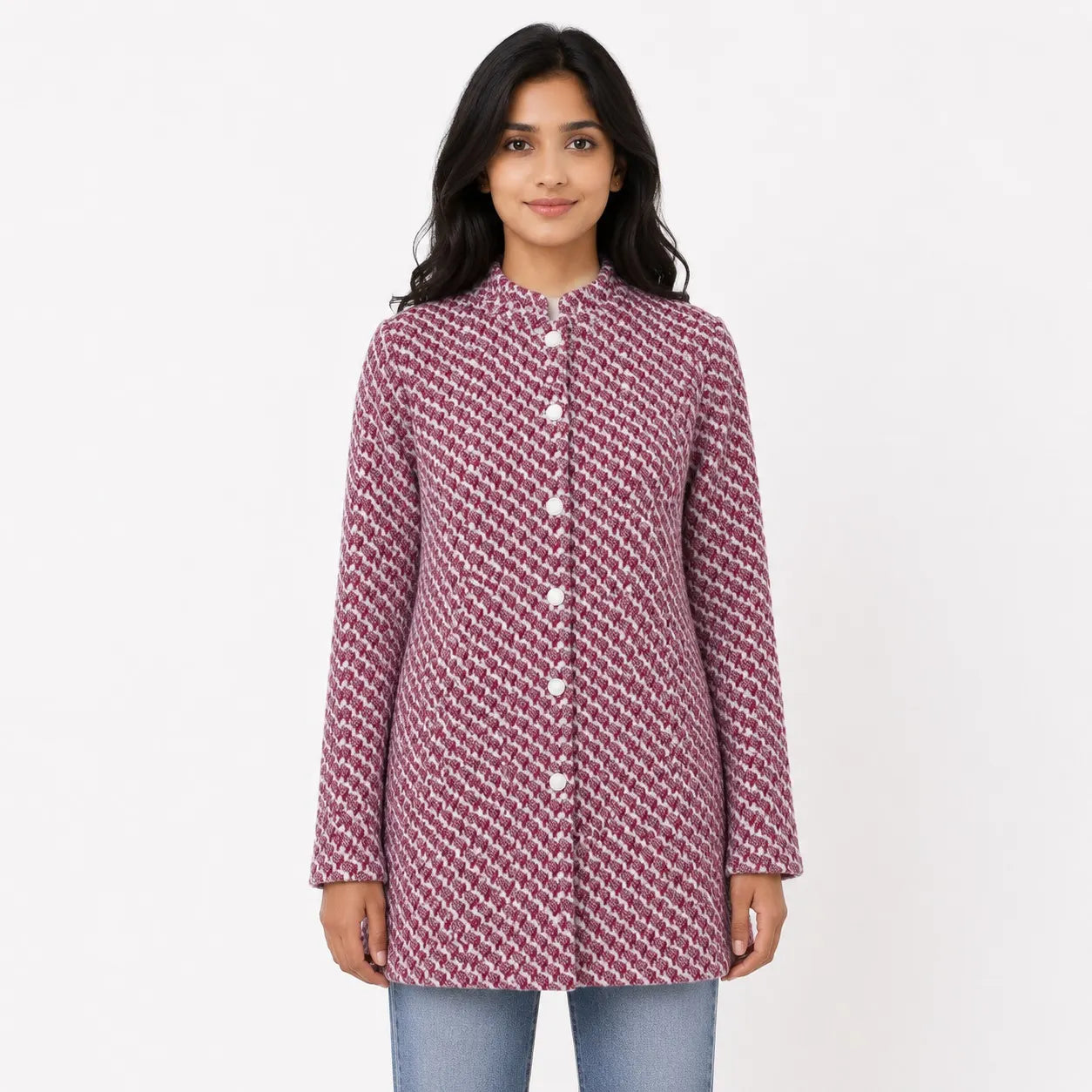 A young woman modeling a long-sleeve, mandarin-collar tunic top with a textured, woven geometric pattern in dusty rose and white, paired with light blue jeans against a plain white studio background.