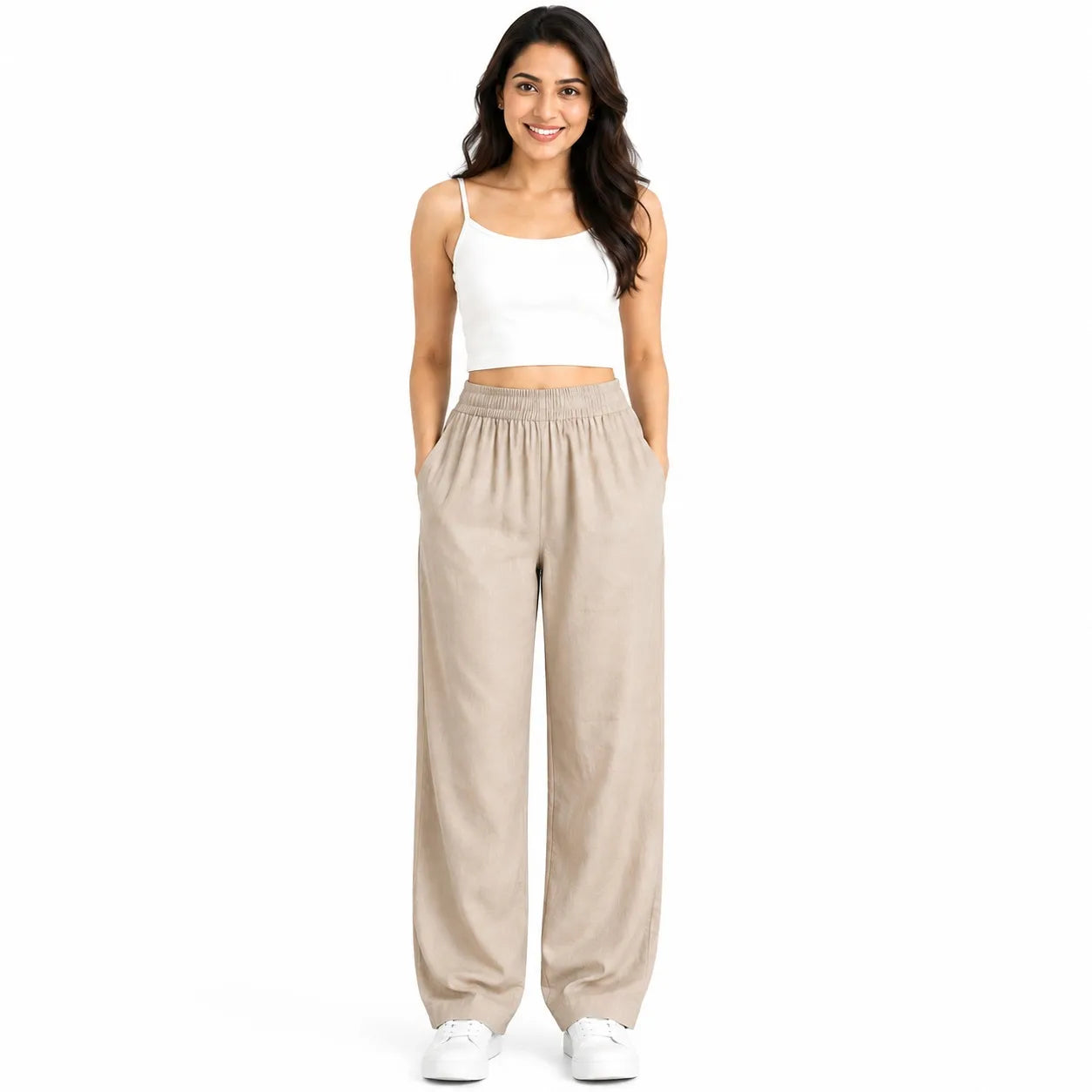 A woman modeling a two-piece outfit consisting of a white spaghetti-strap crop top and beige wide-leg lounge pants, standing against a solid white background.