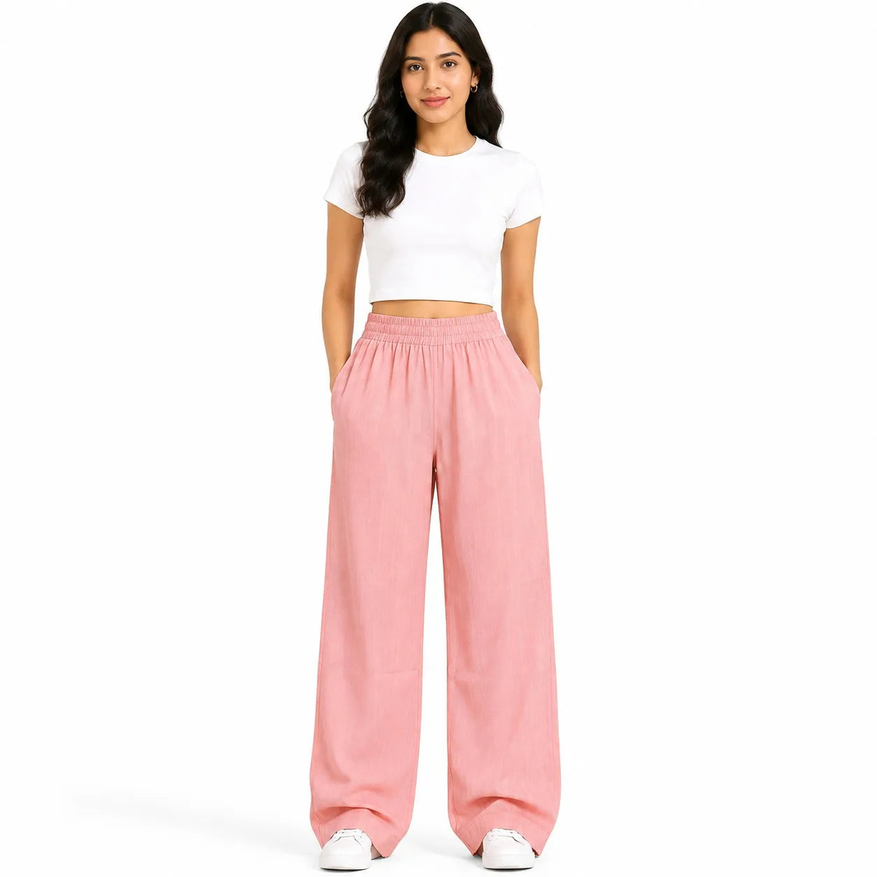 A woman modeling a two-piece outfit consisting of a white short-sleeve crop top and pink wide-leg pants, standing against a solid white background.