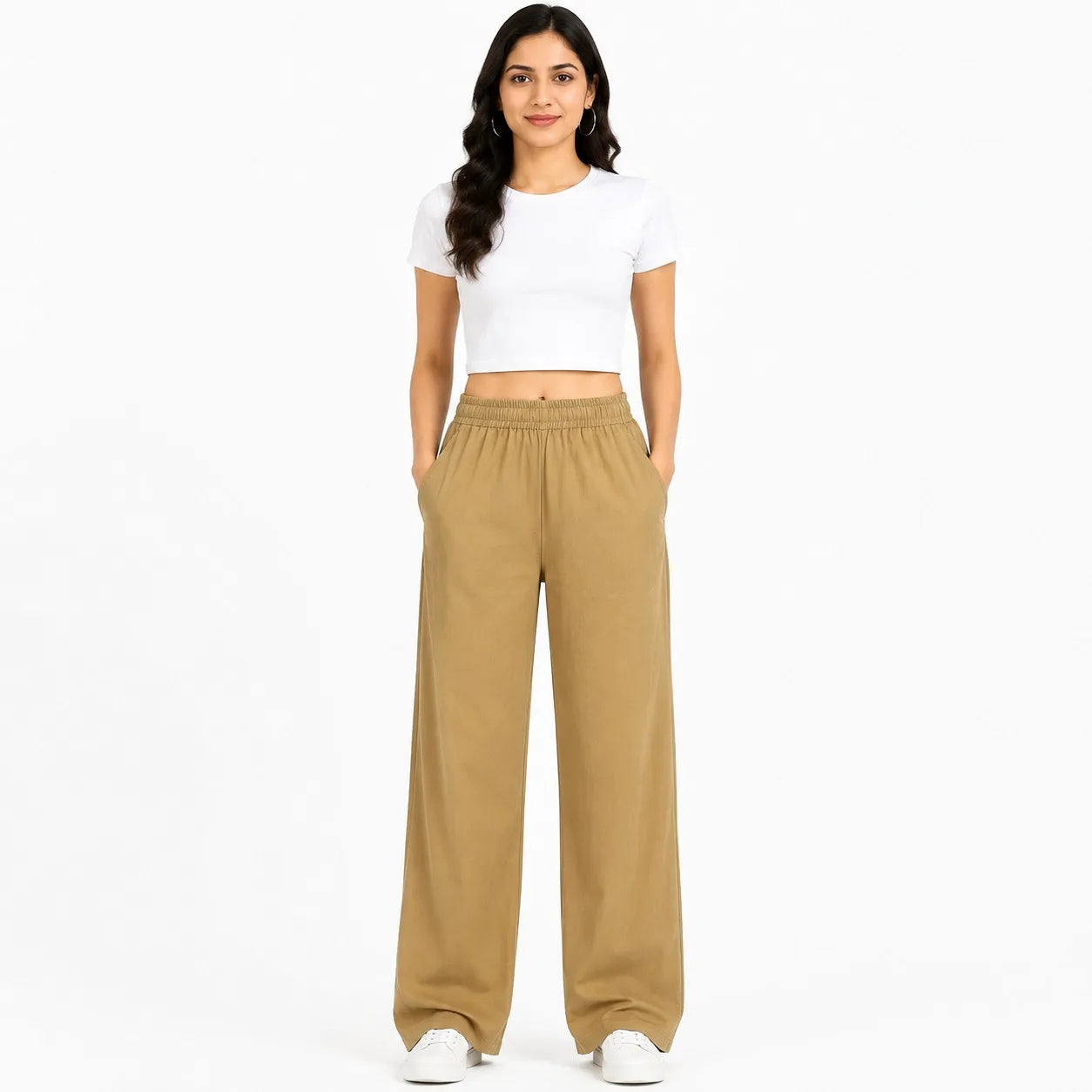 A woman modeling a white short-sleeve crop top and tan wide-leg sweatpants against a plain white studio background.