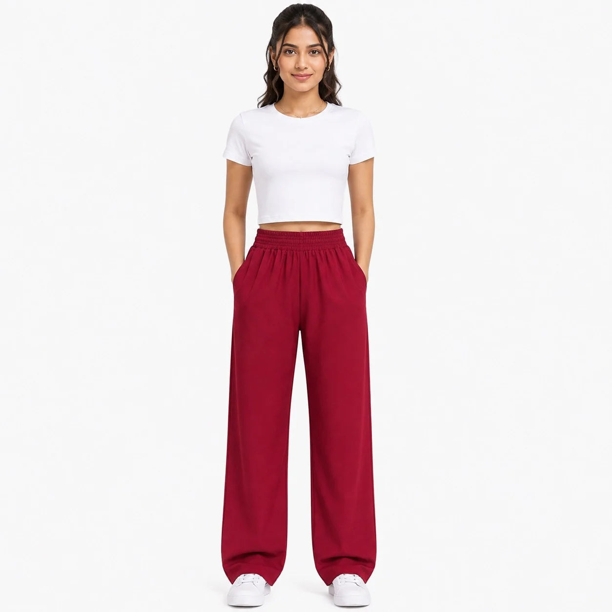 A woman modeling a white short-sleeve crop top and deep red wide-leg sweatpants against a plain white background.