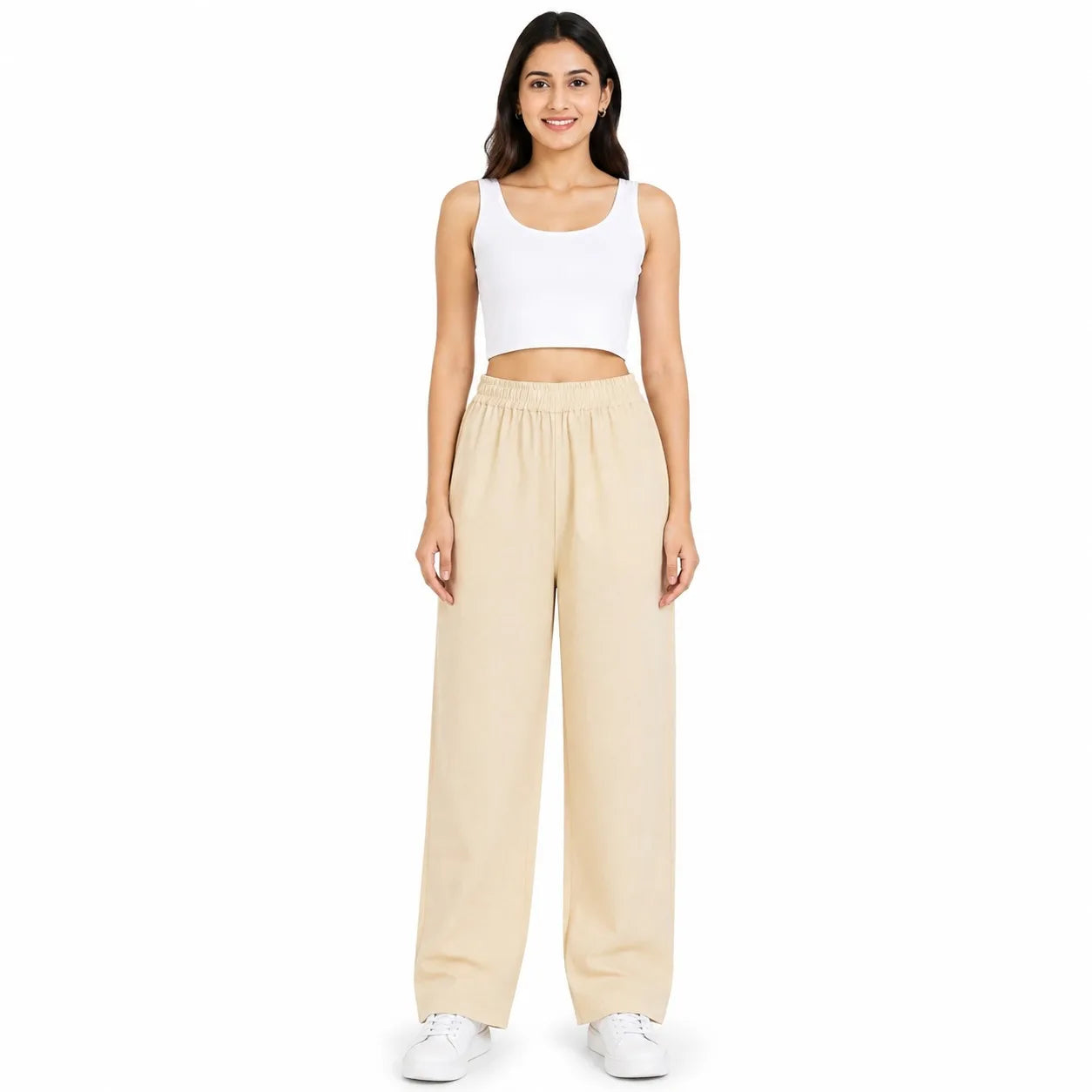 A woman modeling a two-piece lounge set consisting of a white cropped tank top and beige wide-leg sweatpants, paired with white sneakers, against a plain white background.