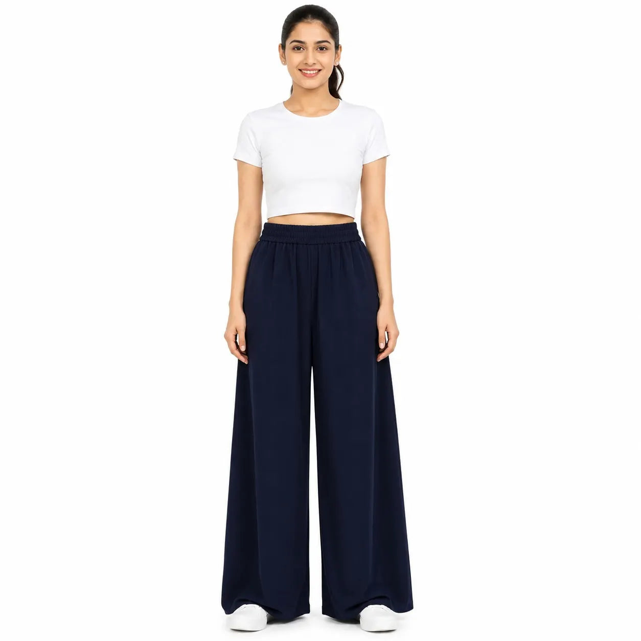 A woman modeling a two-piece outfit consisting of a white short-sleeve crop top and navy blue wide-leg pants, standing against a solid white background.