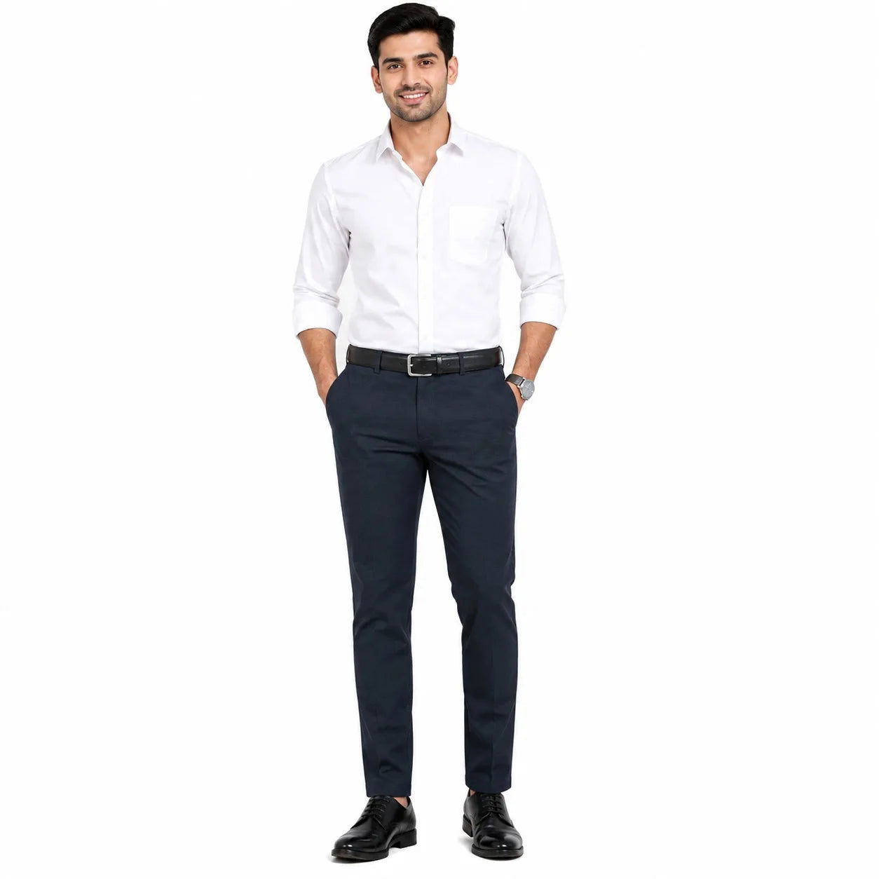A man modeling a white long-sleeve button-down shirt and dark navy trousers with a black belt and black dress shoes, standing against a plain white background.