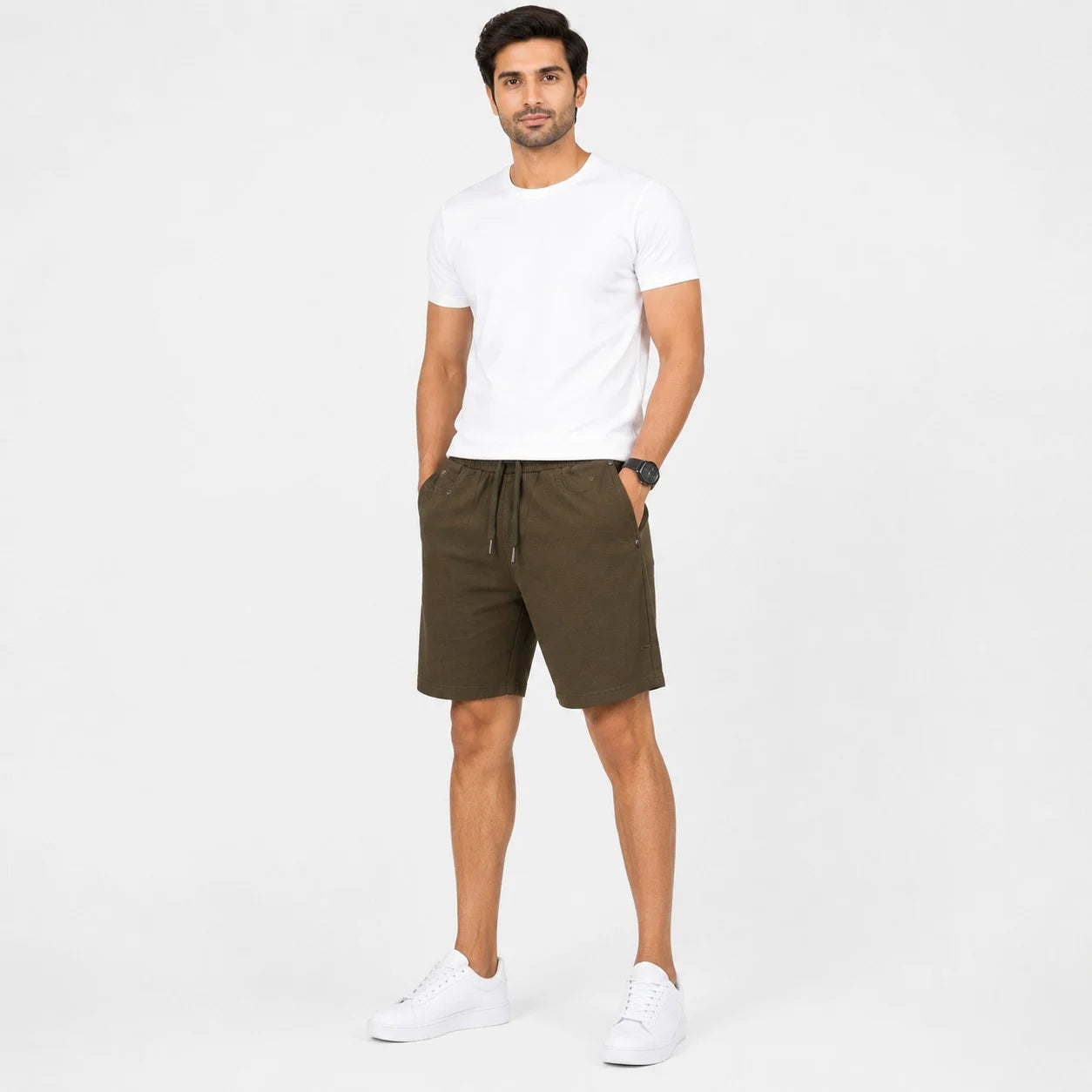A man modeling a white crew-neck t-shirt and dark olive green drawstring shorts against a plain white studio background.