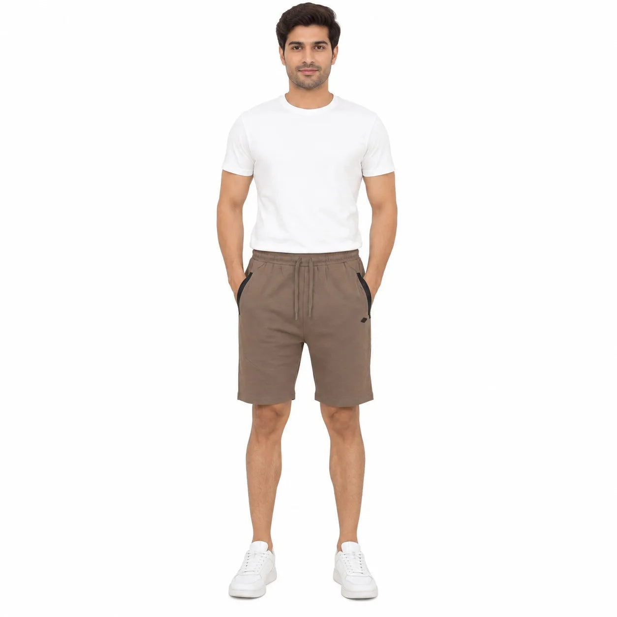 A man modeling a pair of brown drawstring shorts with black side panels, paired with a white t-shirt and white sneakers, against a plain white background.
