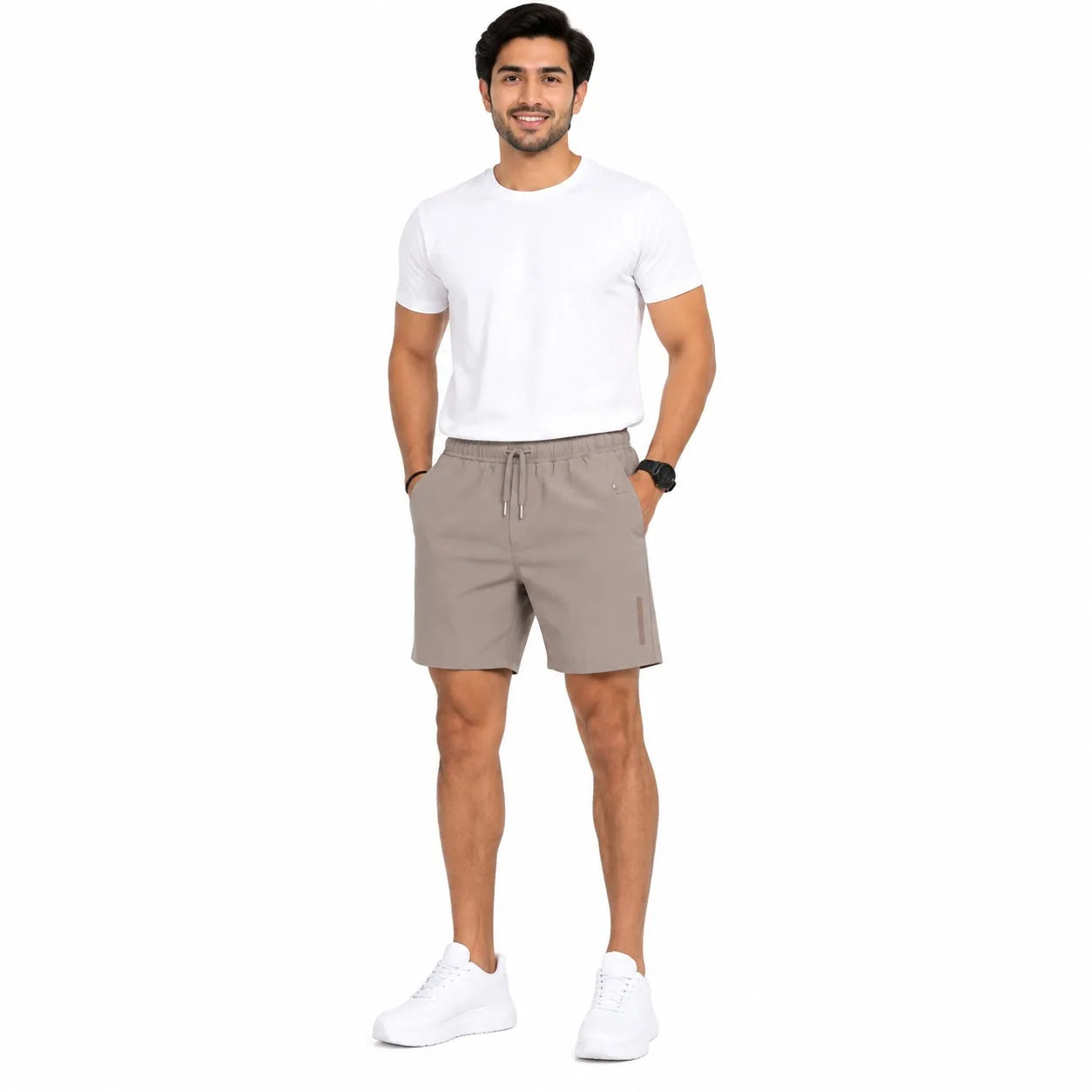 A man modeling a pair of light brown drawstring shorts, paired with a white t-shirt and white sneakers, standing against a solid white background.