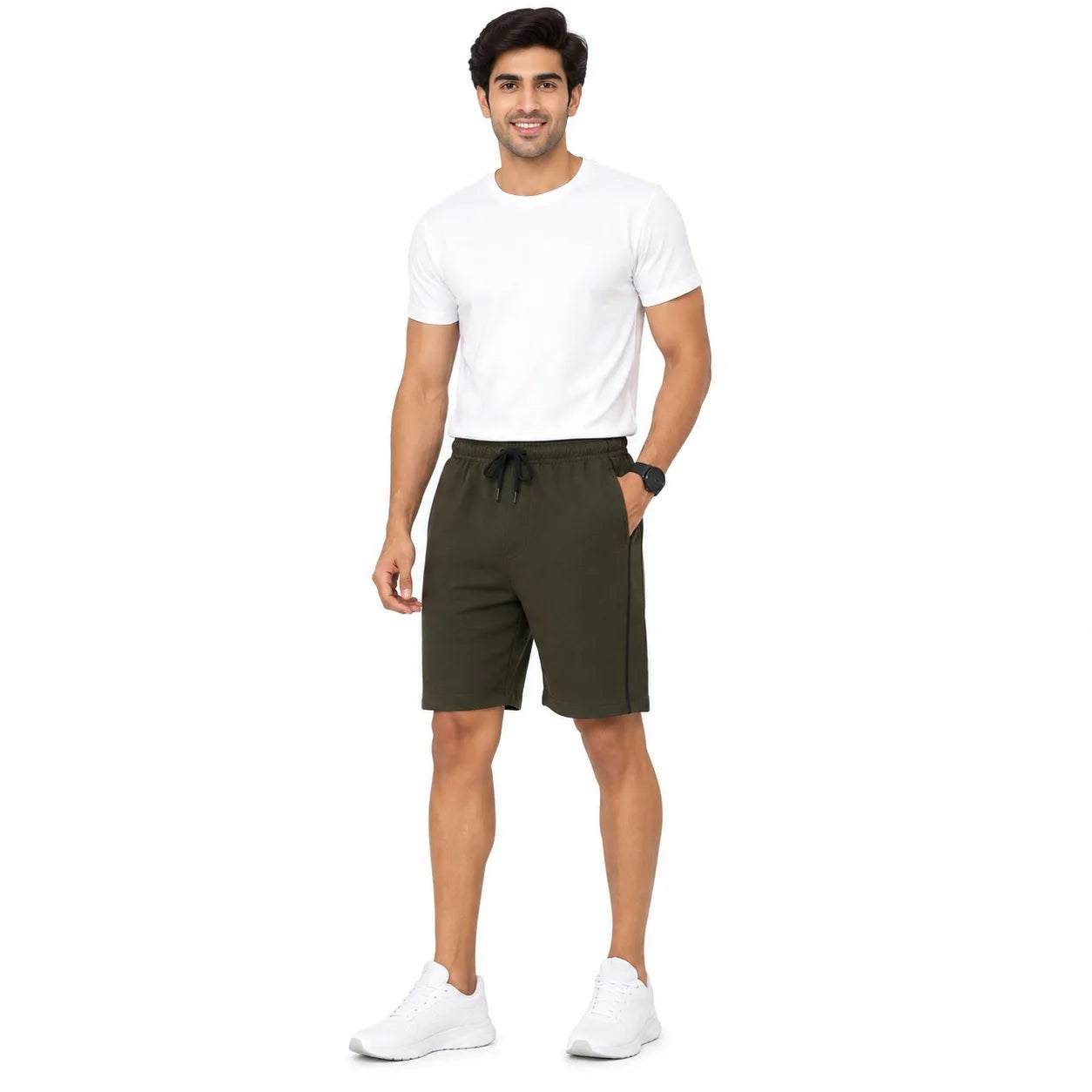 A man modeling dark olive green drawstring shorts, paired with a white t-shirt and white sneakers, standing against a solid white background.