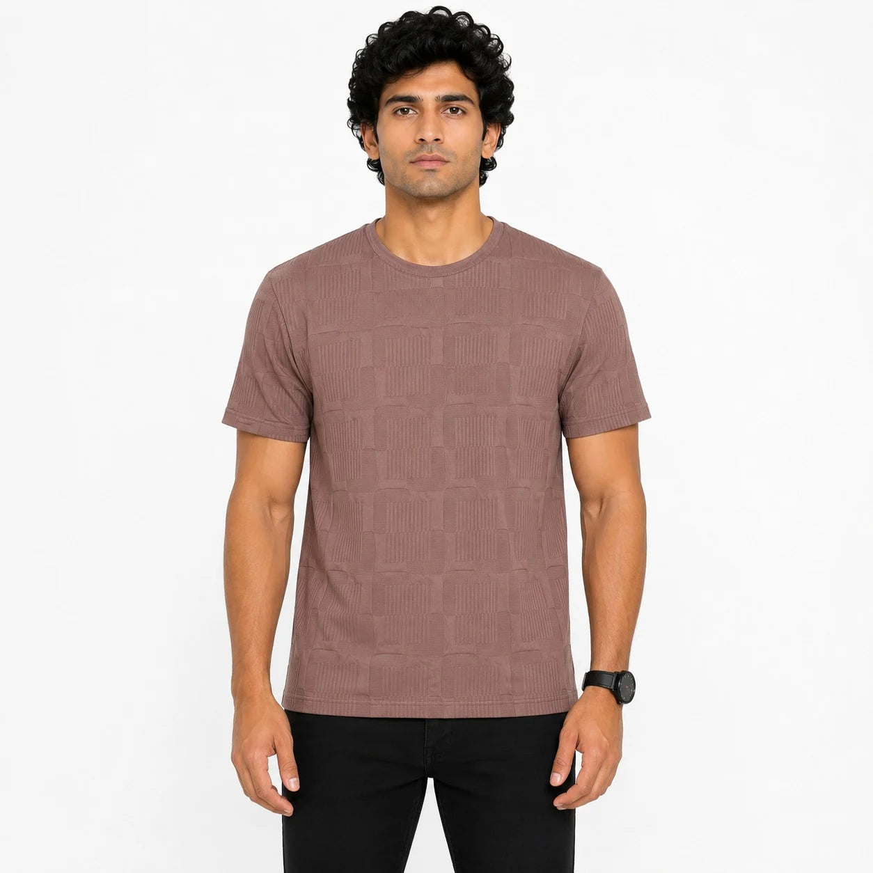 A man wearing a short-sleeve crewneck t-shirt in a dusty rose color with a subtle geometric pattern, paired with black pants, standing against a plain white background.