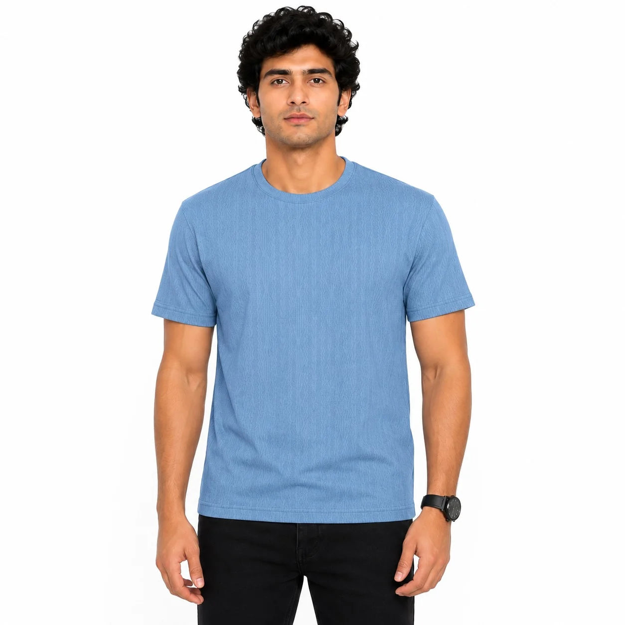 A man wearing a heathered light blue crew-neck t-shirt and black pants, standing against a solid white background.