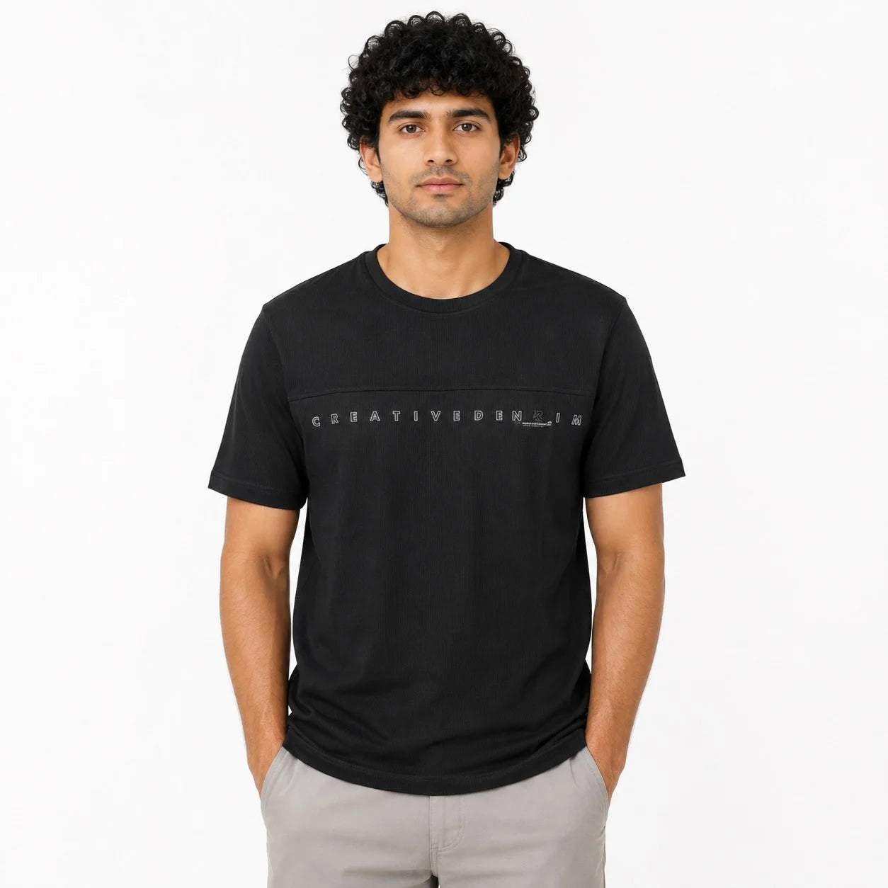 A man wearing a black short-sleeve t-shirt with a horizontal graphic text 'CREATIVEHONSH' printed across the chest, paired with light gray pants, against a plain white background.