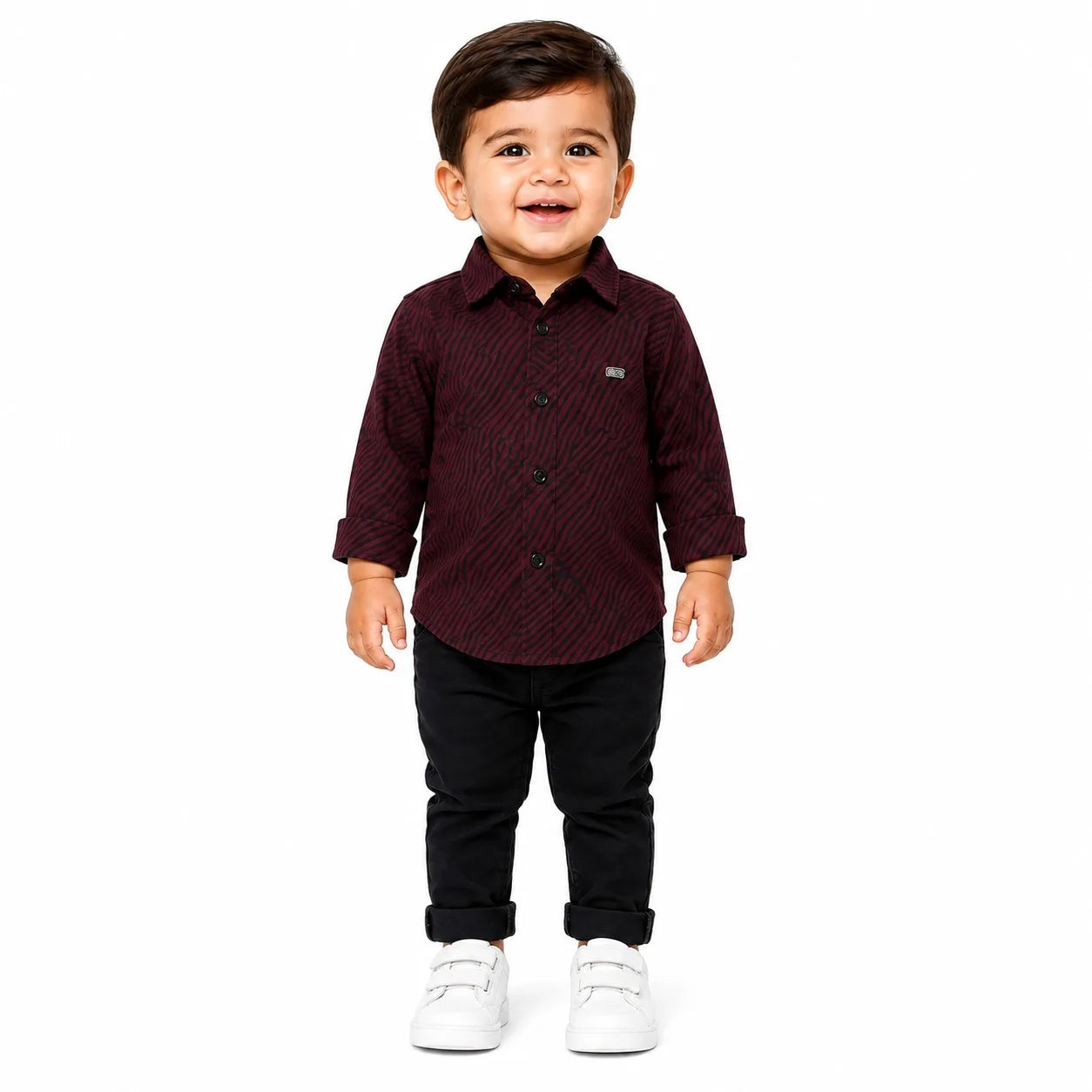 A toddler boy standing against a white background, wearing a dark burgundy long-sleeve button-up shirt with a subtle diagonal textured pattern, black pants, and white sneakers.