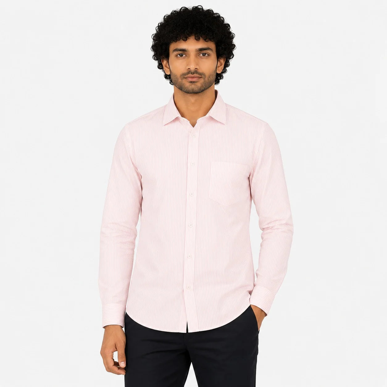 A man wearing a light pink long-sleeve button-up shirt with a subtle vertical stripe pattern and a single chest pocket, paired with black trousers, against a plain white background.